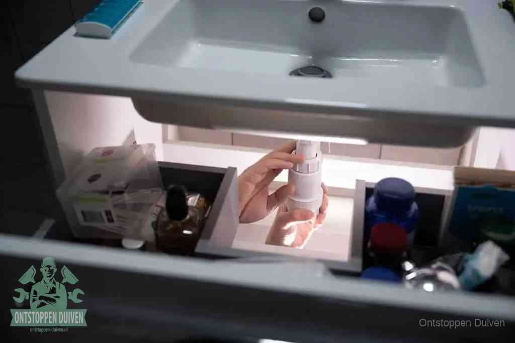 Een pompfles met zeep boven een wastafel, de heet water en afwasmiddel-methode om een vetprop in de afvoer los te maken in Duiven