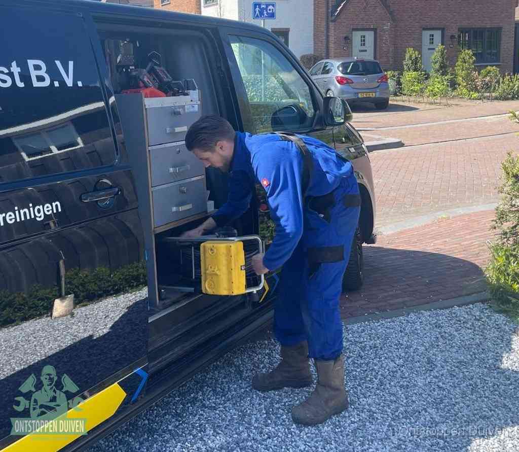 Een monteur pakt buiten op de oprit gereedschap uit de bedrijfsbus, het moment om een professional in te schakelen voor een verstopte afvoer in Duiven