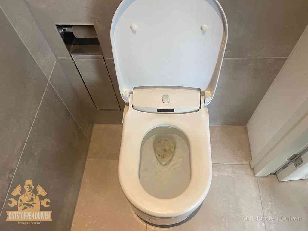 Een wit hangtoilet waarin een prop wc-papier op het water blijft drijven, een duidelijk signaal van een verstopte wc in Duiven