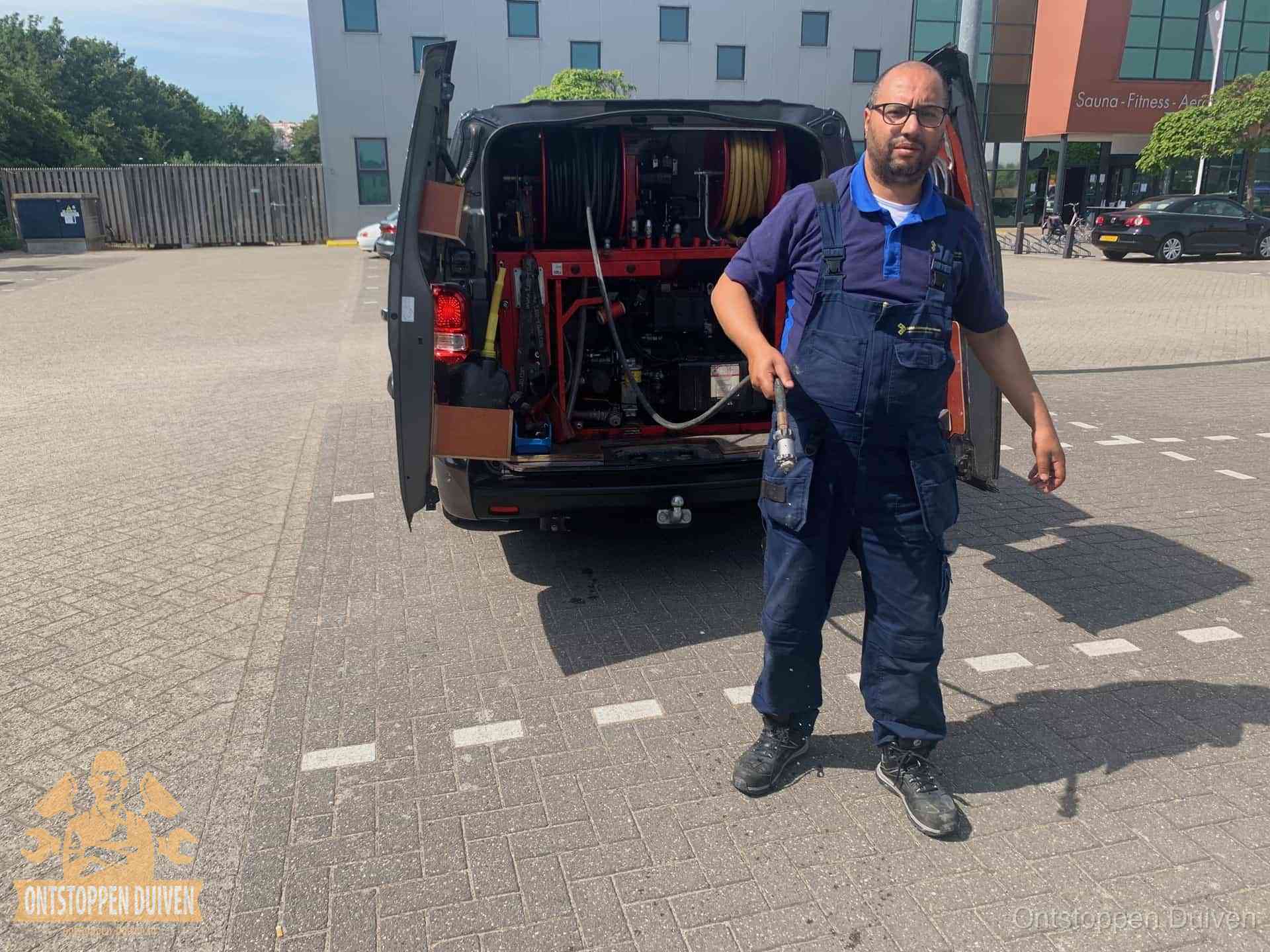 Een monteur bij zijn bestelbus met een hogedruk- en rioolreinigingsunit, klaar om de oorzaak van terugkerende wc-verstoppingen aan te pakken in Duiven