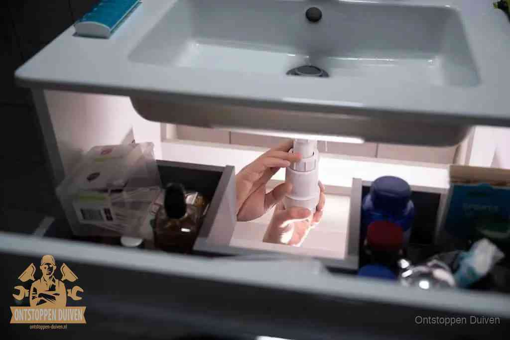 Een pompfles met zeep boven een wastafel in de toiletruimte, de warm water en afwasmiddel-methode om de wc te ontstoppen in Duiven