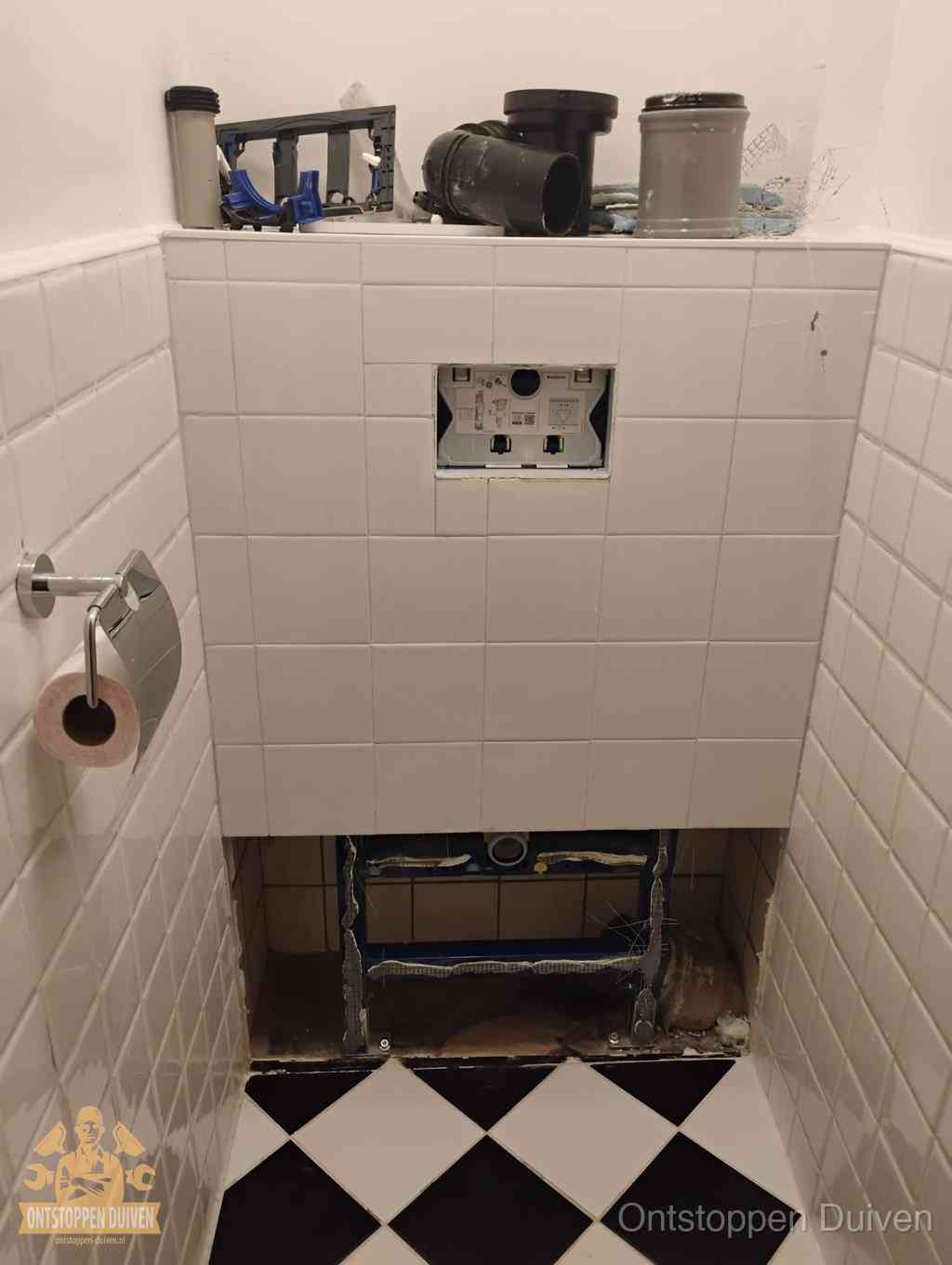Een toiletruimte waar het hangtoilet en de inbouwreservoir-onderdelen zijn vrijgelegd voor onderhoud, periodiek nazicht voorkomt een wc-verstopping in Duiven