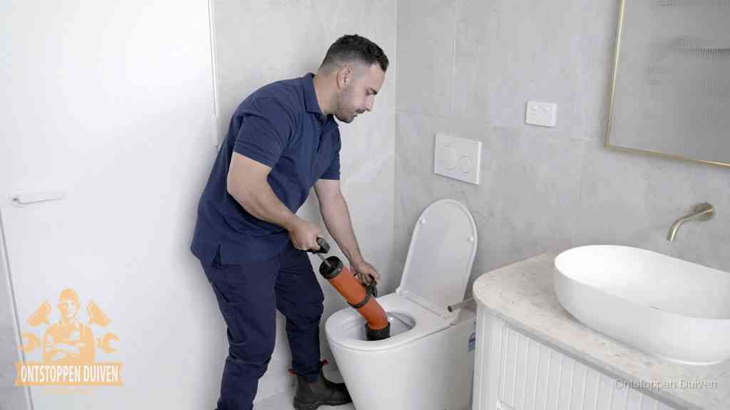 Een monteur gebruikt een handmatige perspomp (toiletontstopper) op een wandcloset tijdens het professioneel wc ontstoppen in Duiven