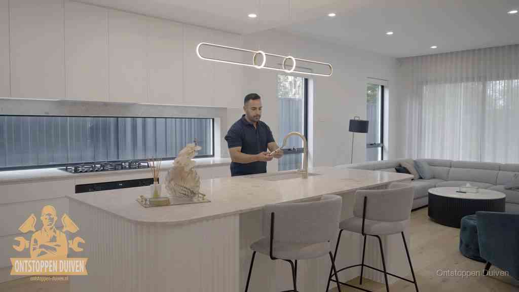 Een bewoner bij de keukenspoelbak die zelf aan de slag gaat met een verstopte gootsteen in Duiven Een bewoner bij de keukenspoelbak die zelf aan de slag gaat met een verstopte gootsteen in Duiven